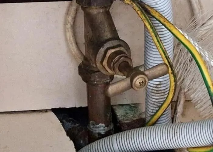 A corroded brass stopcock on old copper pipe, of the kind that seizes and needs replacing
