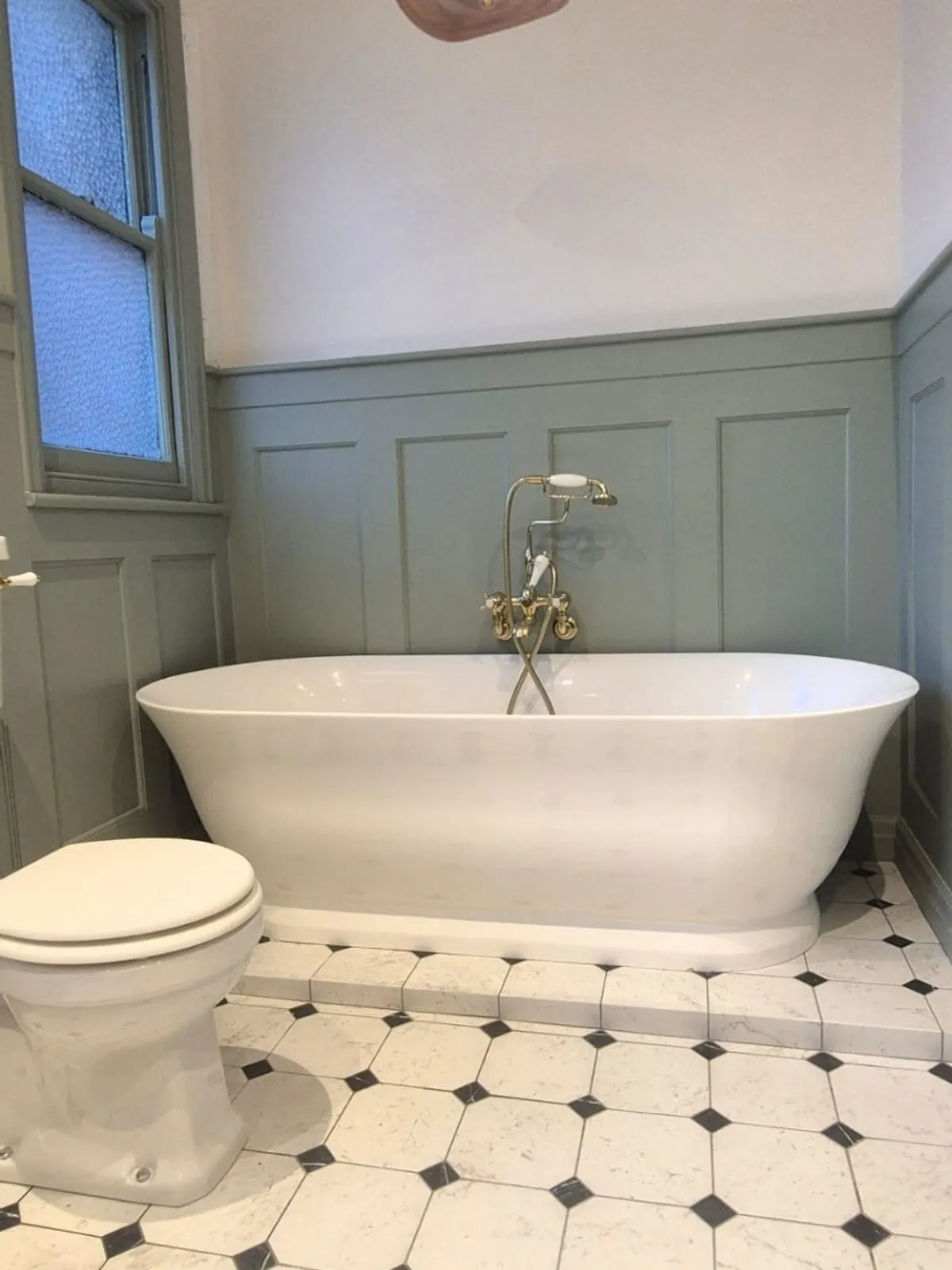 The finished bathroom showing the low level toilet, freestanding bath and full height panelling