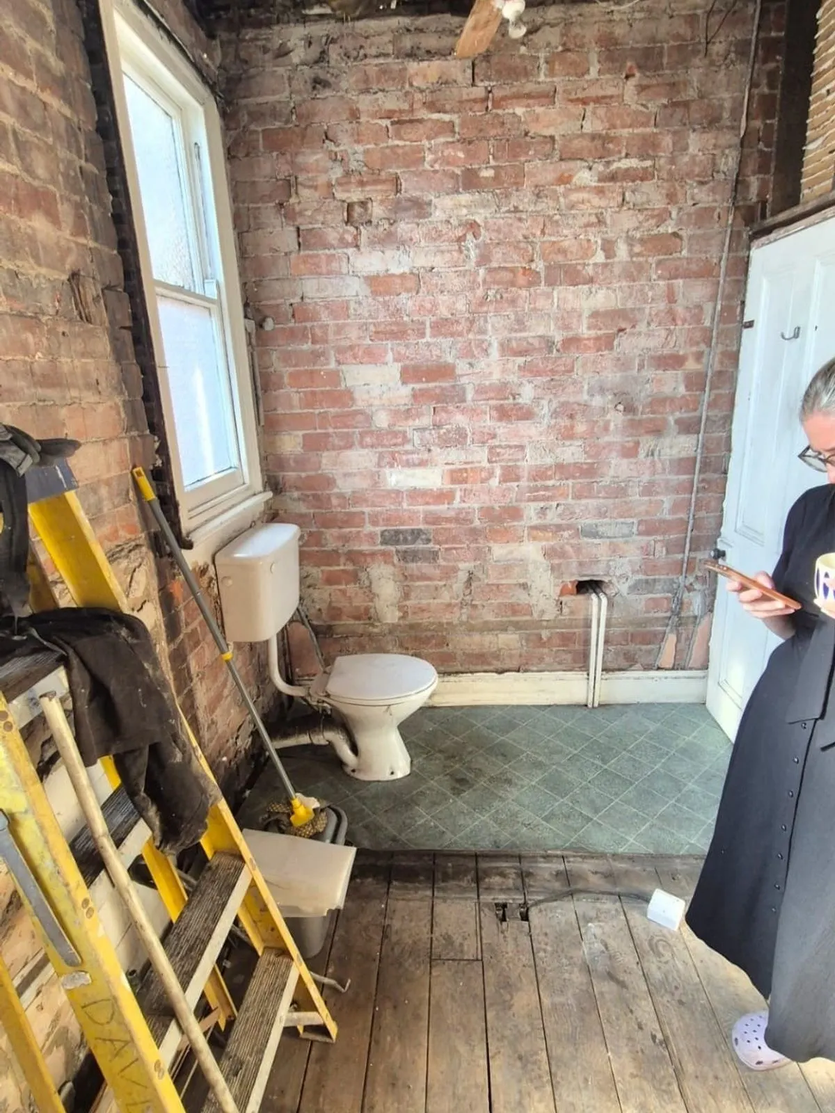 The same room from the opposite corner, showing two sash windows and exposed lath and plaster