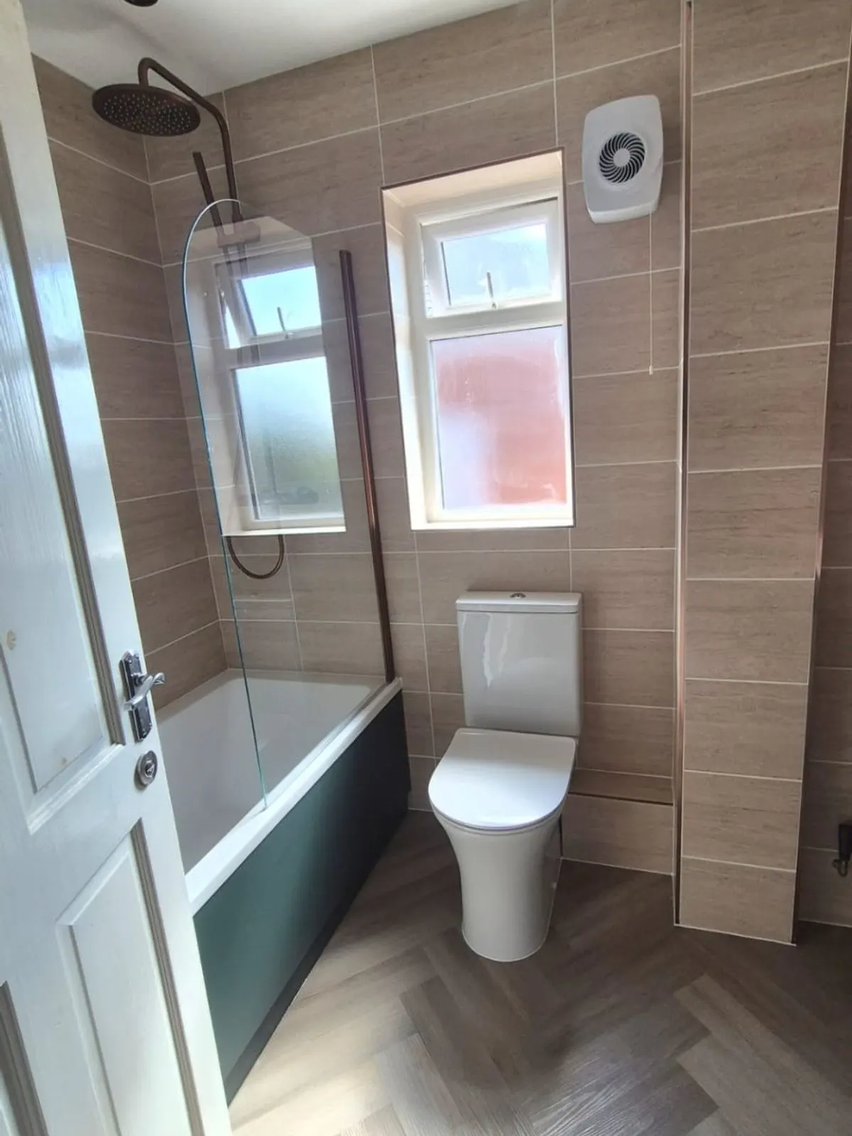 The finished bath and copper shower set against large format tiling with herringbone flooring