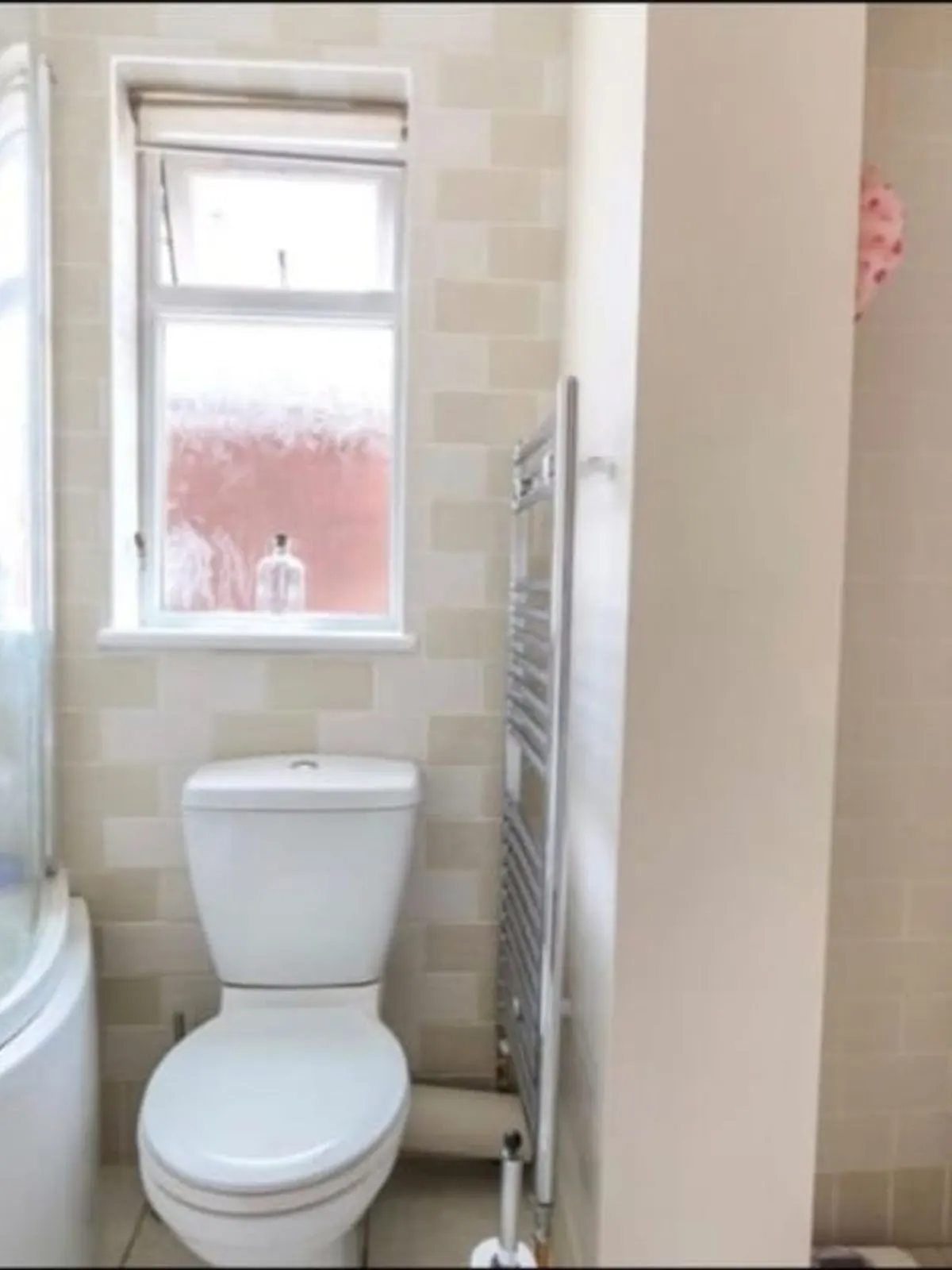 The original cream tiled bathroom with a curved shower bath and dated vanity unit